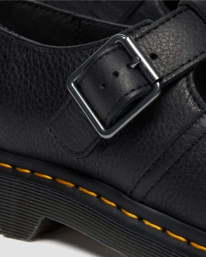 Close-up of a black leather shoe with a buckle and yellow stitching detail.