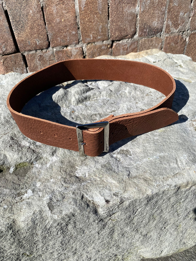 Brown leather belt on a stone surface