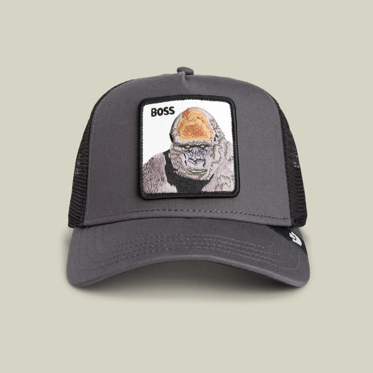 Gray trucker cap with a gorilla patch and 'BOSS' text on a beige background