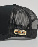 Black mesh cap with a gold patch on a gray background