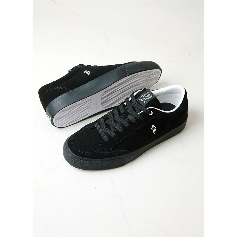 A pair of black suede skate shoes with white details, designed by Dustin Dollin.