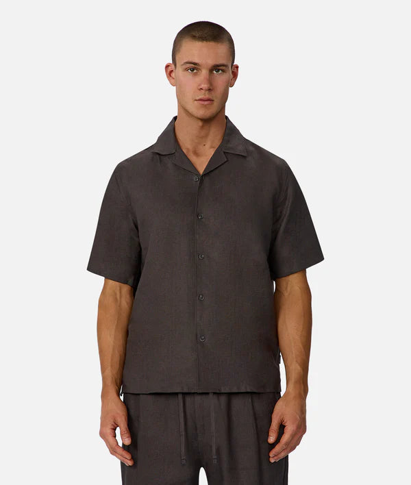 Man wearing a dark brown short-sleeve shirt and pants on a white background