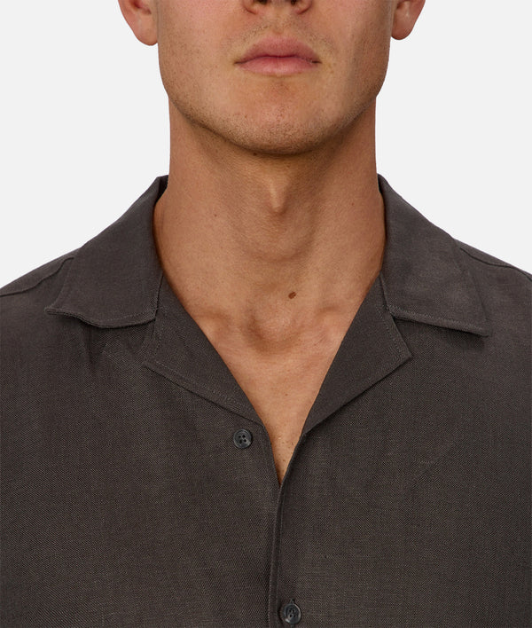 Close-up of a man wearing a dark brown button-up shirt on a white background