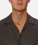 Close-up of a man wearing a dark brown button-up shirt on a white background