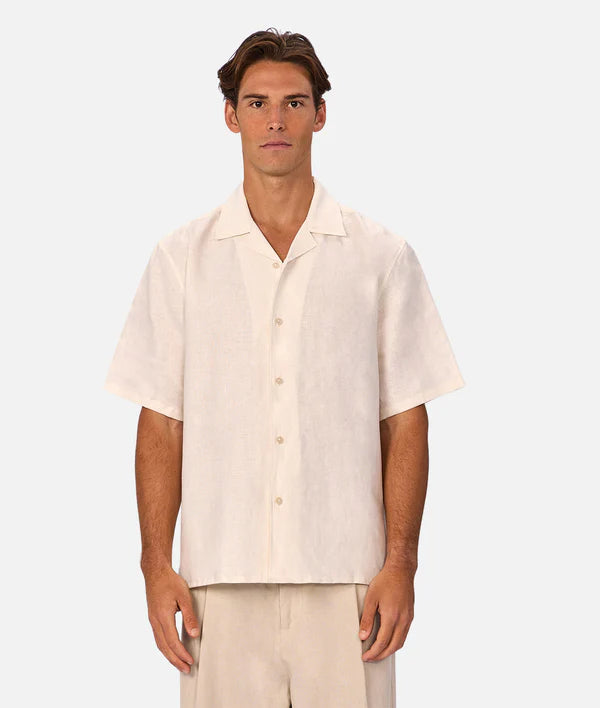 Man wearing a beige short-sleeve shirt and pants on a white background