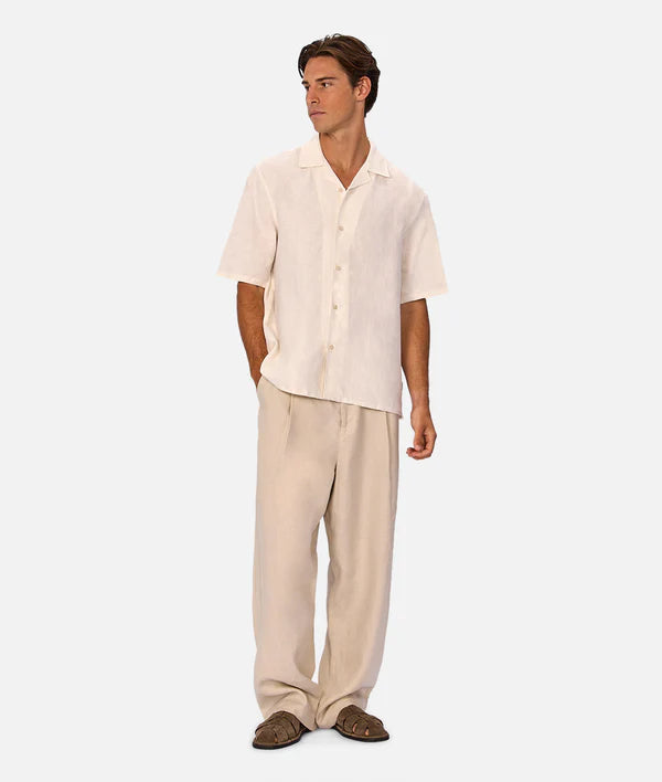 Man wearing a beige linen shirt and pants on a white background