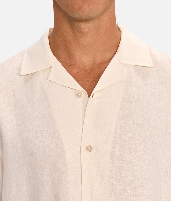 Close-up of a beige button-up shirt worn by a person on a light background