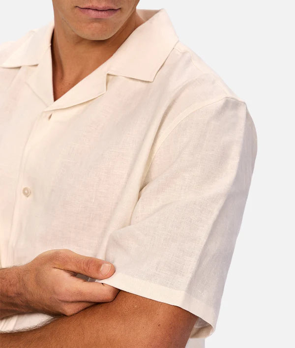 Close-up of a person wearing a light-colored shirt with short sleeves on a white background