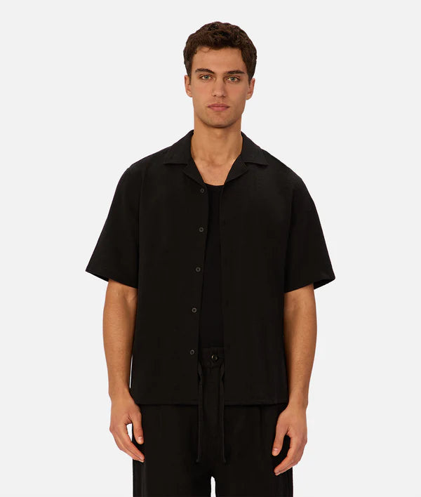 Man wearing a black short-sleeve button-up shirt on a white background