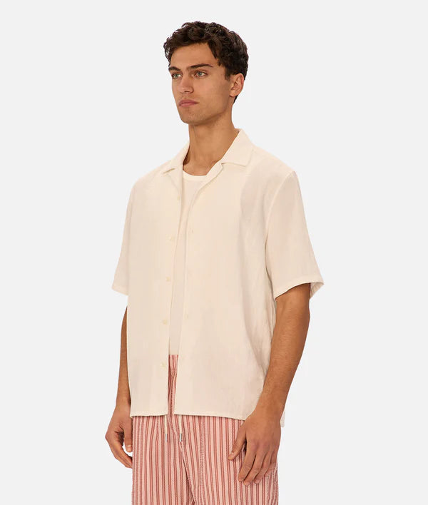 Man wearing a beige short-sleeve shirt and red striped pants on a white background