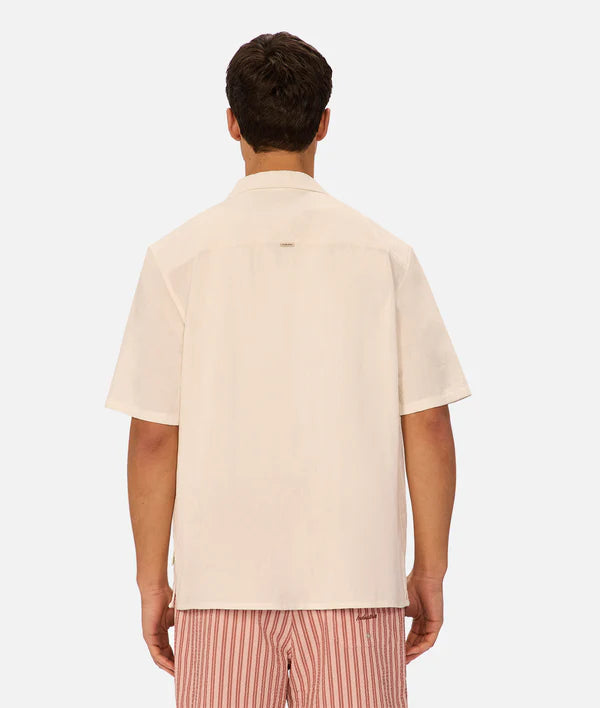Man wearing a beige short-sleeve shirt and striped pants on a white background