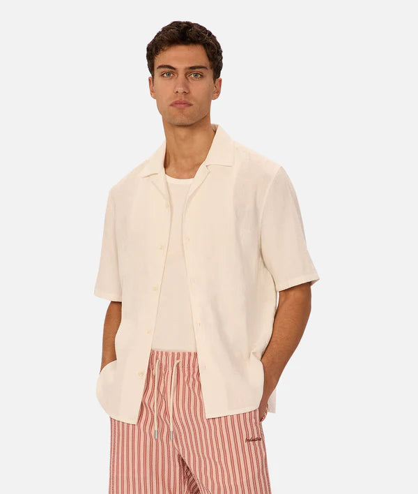 Man wearing a beige shirt and red striped pants on a white background