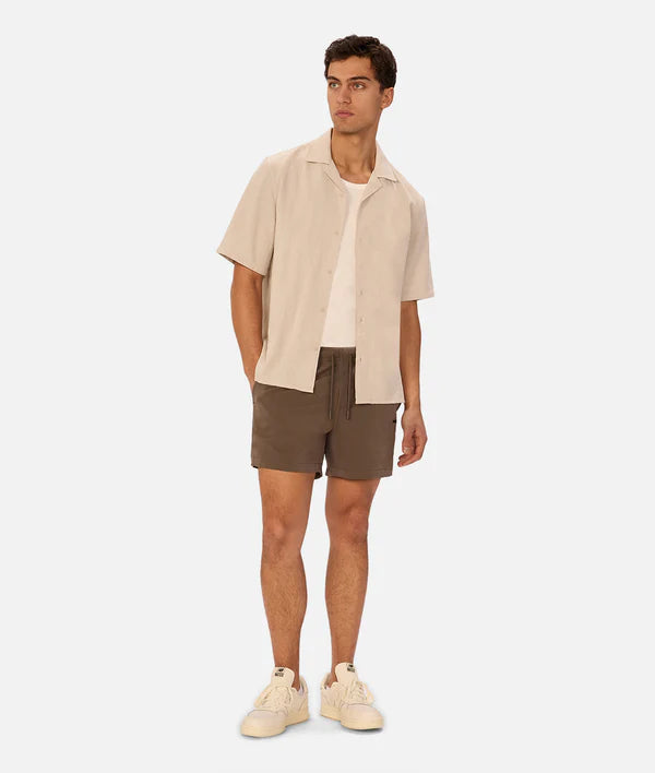 Man wearing a beige shirt and brown shorts on a white background