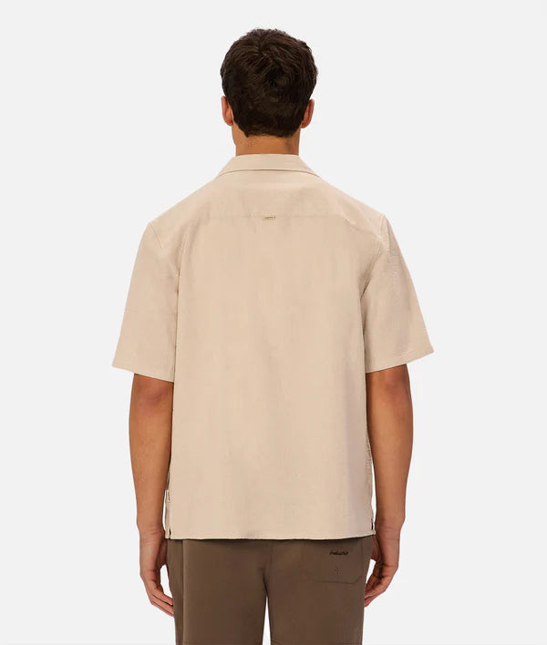 Man wearing a beige short-sleeve shirt on a white background