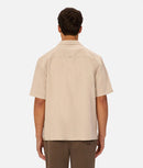 Man wearing a beige short-sleeve shirt on a white background