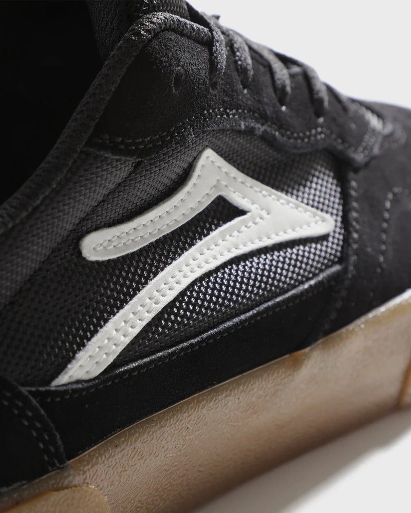 Close-up of a black sneaker with a white logo on a light background
