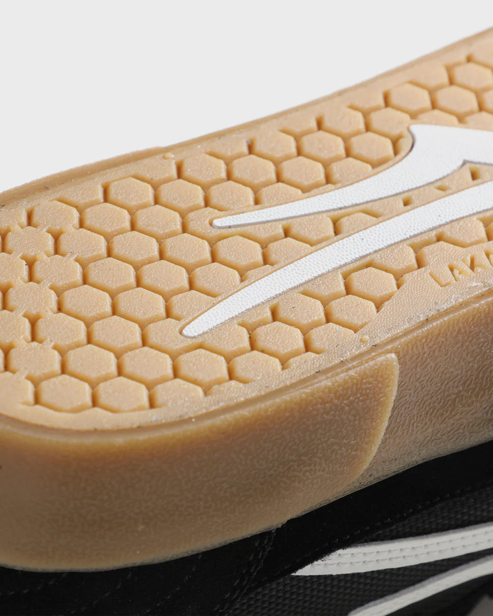Close-up of a shoe sole with a honeycomb pattern and a white logo on a light background