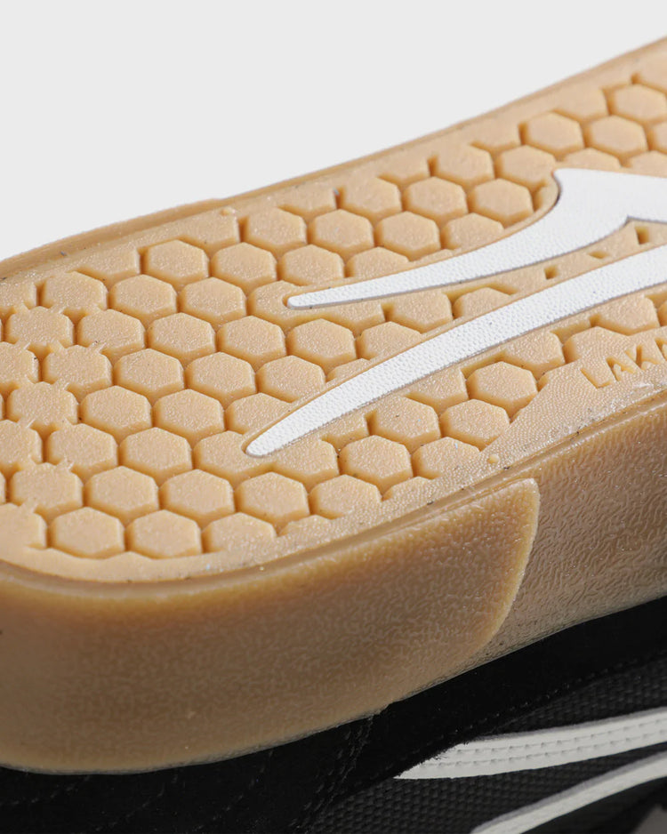 Close-up of a shoe sole with a honeycomb pattern and a white logo on a light background