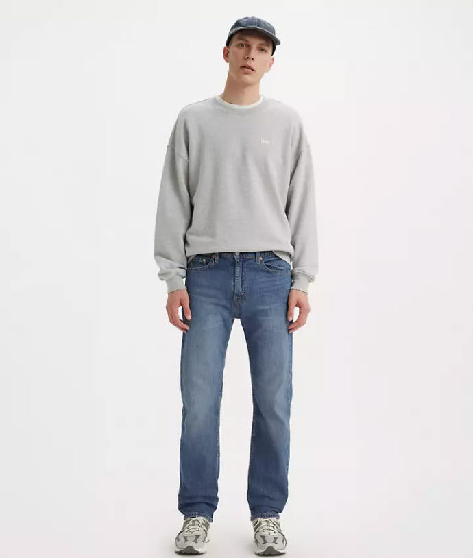 Person wearing a gray sweatshirt and blue jeans on a white background