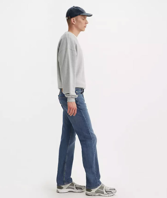 Person wearing a gray sweatshirt, blue jeans, and a cap on a white background