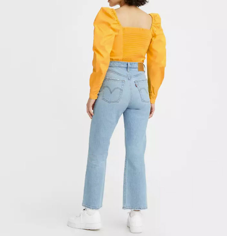 Person wearing a yellow top and light blue jeans on a white background