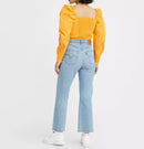 Person wearing a yellow top and light blue jeans on a white background