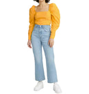 Person wearing a yellow top with puffed sleeves and light blue jeans on a white background