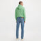 Person wearing a green hoodie and blue jeans on a white background