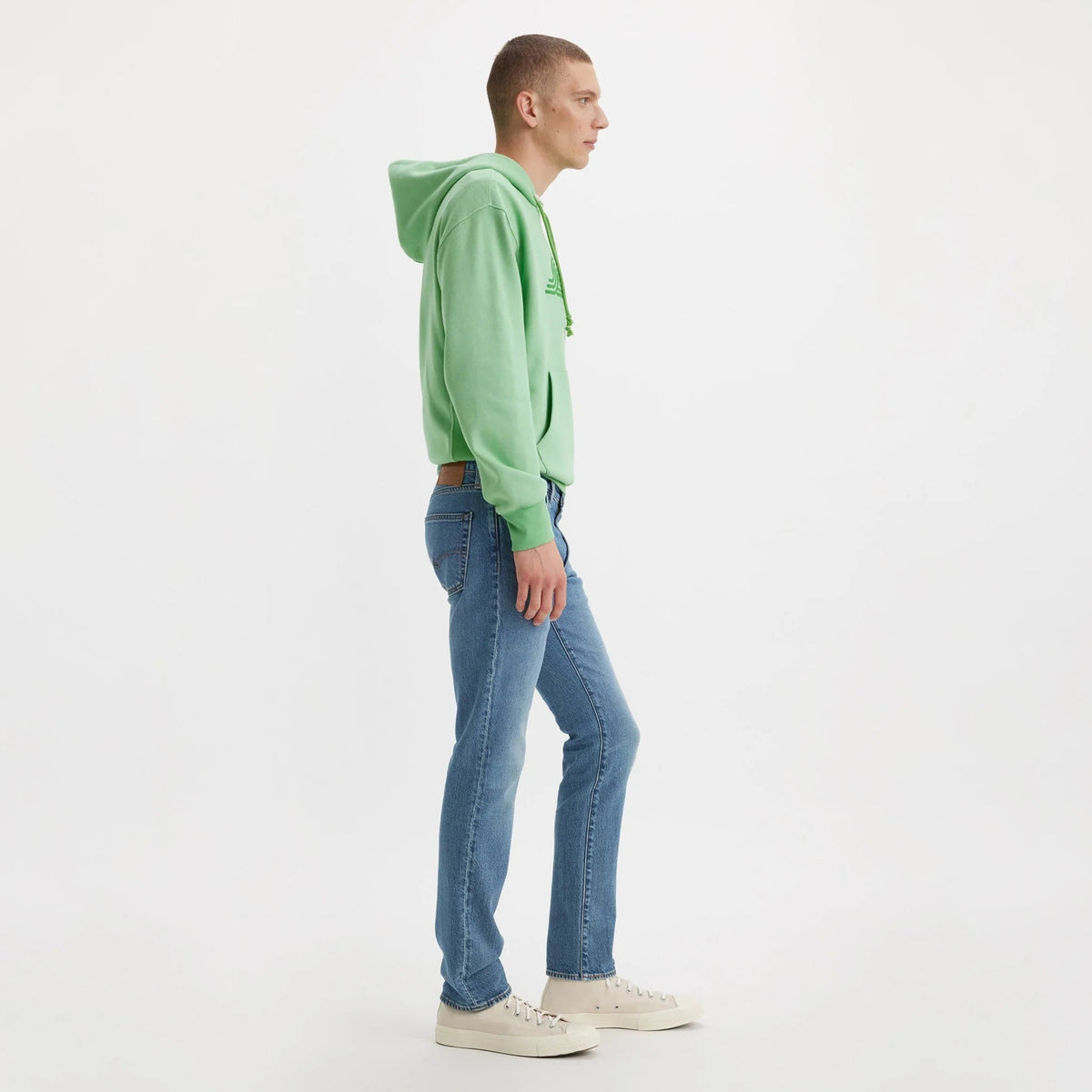 Person wearing a green hoodie and blue jeans on a white background
