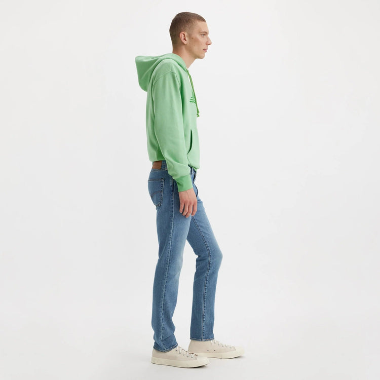 Person wearing a green hoodie and blue jeans on a white background