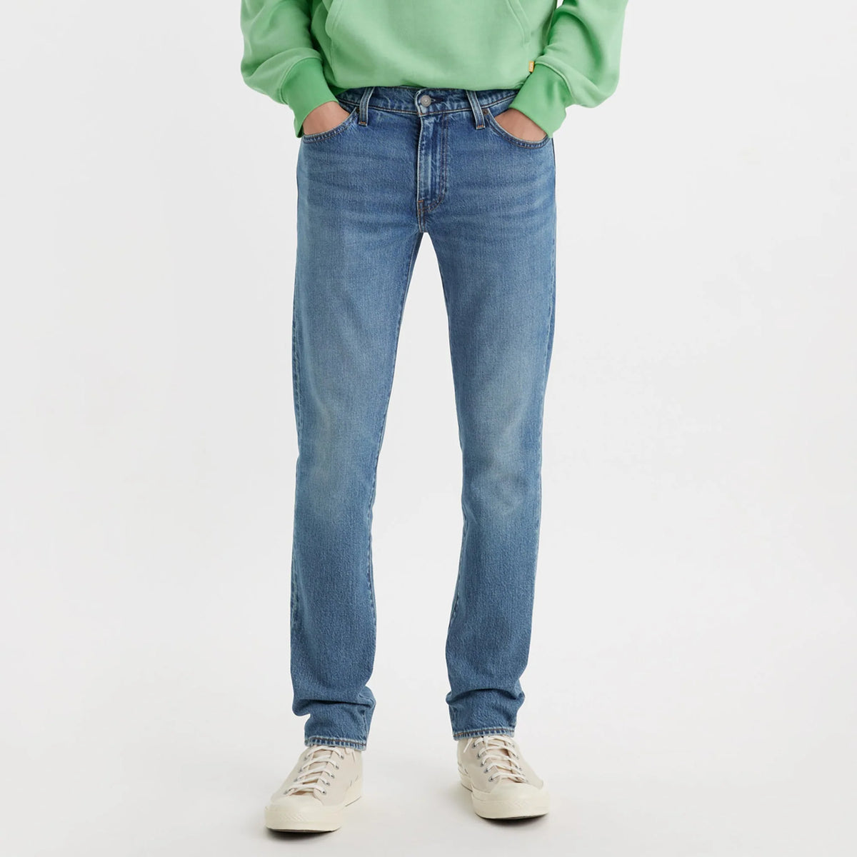 Person wearing blue jeans and a green sweater on a white background