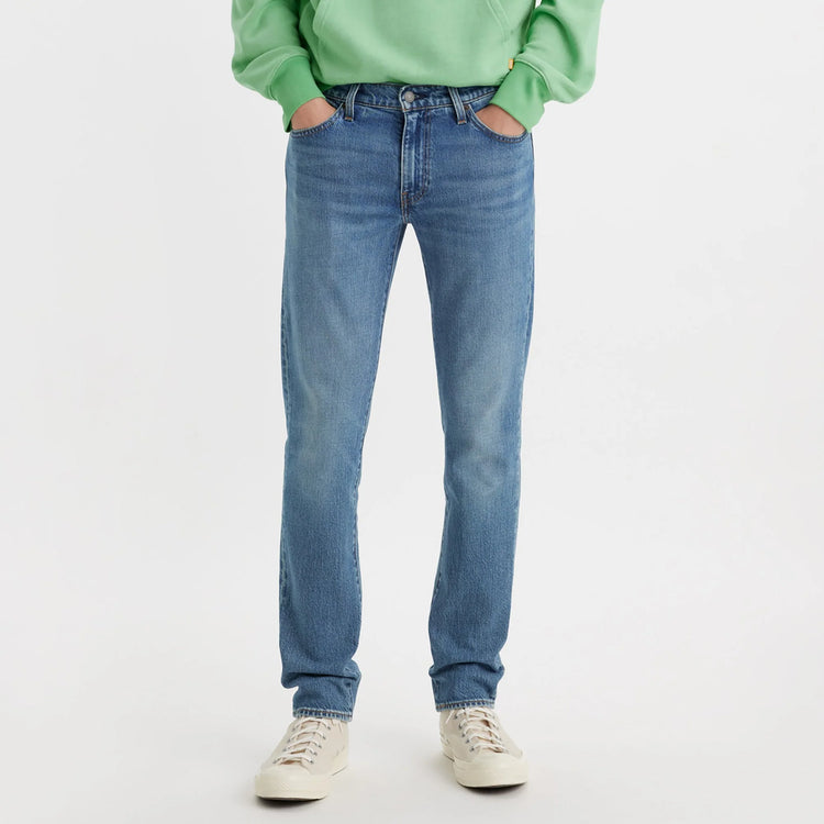 Person wearing blue jeans and a green sweater on a white background