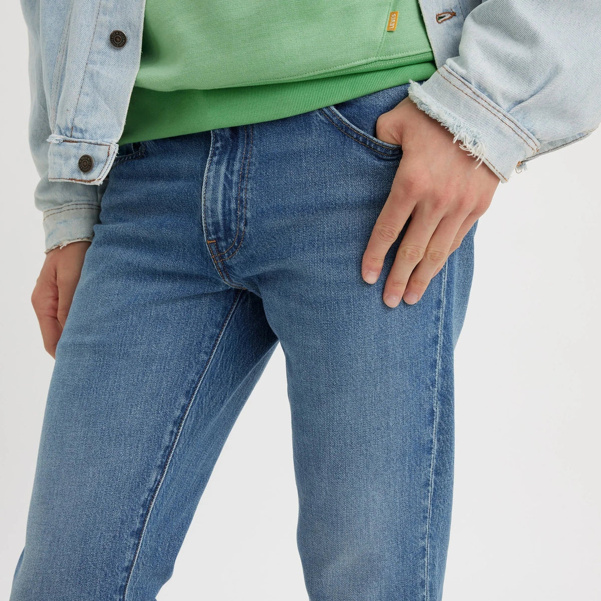 Person wearing blue jeans with a light gray background