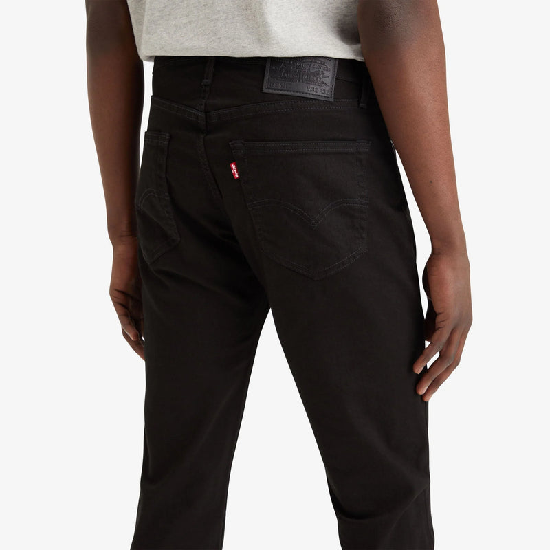 Person wearing black pants with a visible brand logo on a white background