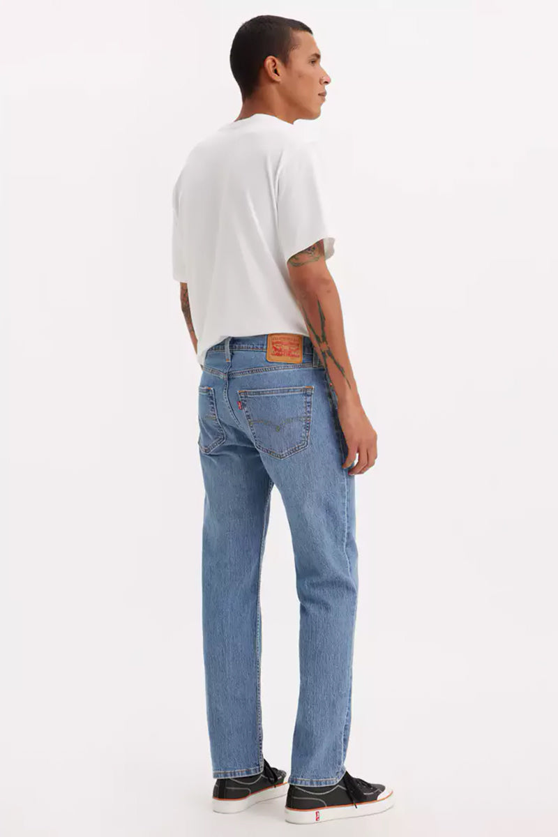 Man wearing light blue jeans and a white t-shirt on a white background