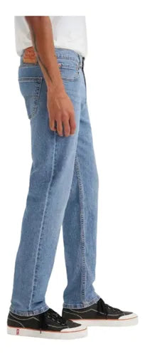 Person wearing light blue jeans and black sneakers on a white background