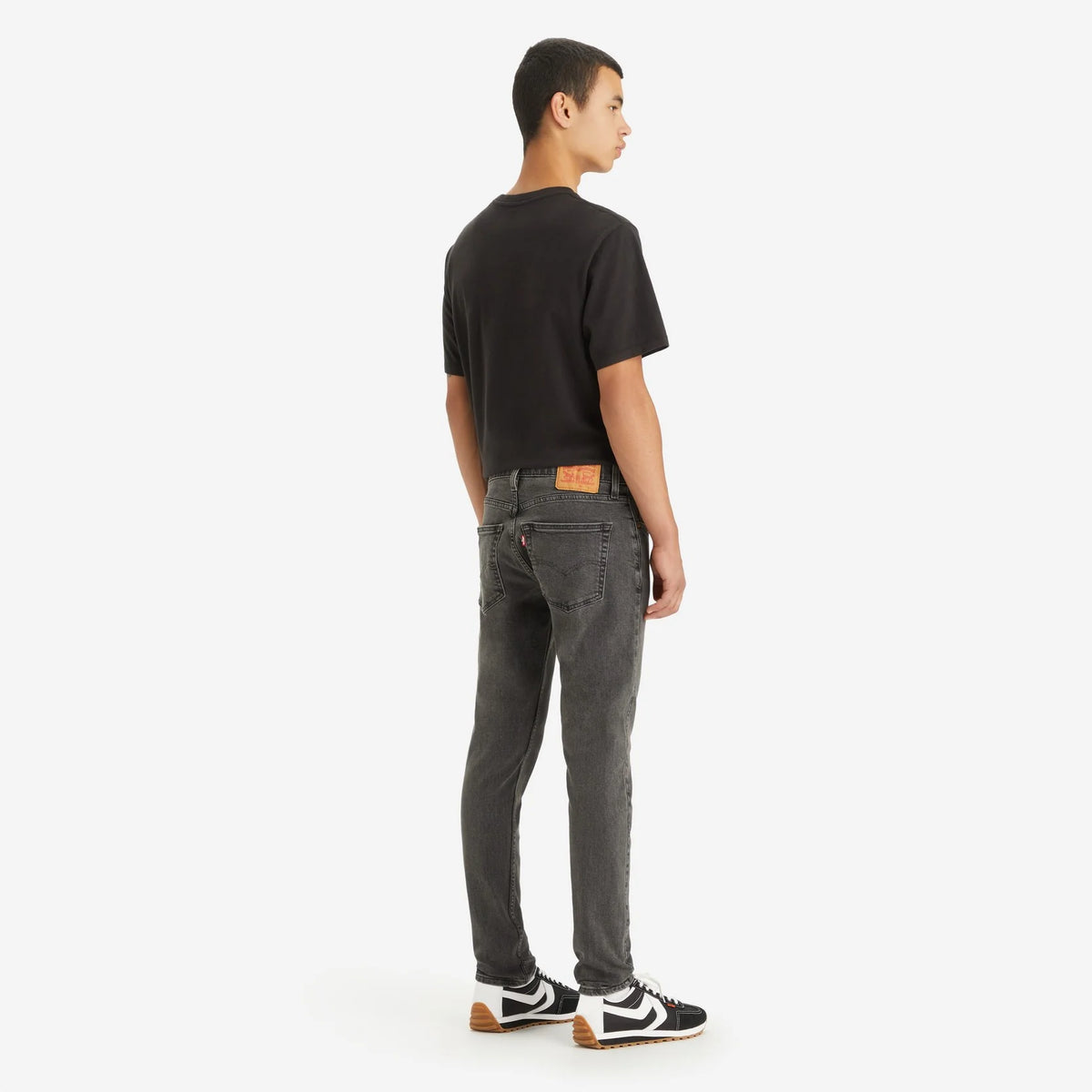 Person wearing gray jeans and a black t-shirt on a white background
