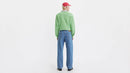 Person wearing a green sweater and blue jeans on a white background