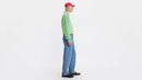 Person wearing a green sweater, blue jeans, and a red cap on a white background