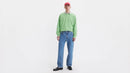 Person wearing a green sweater and blue jeans on a white background