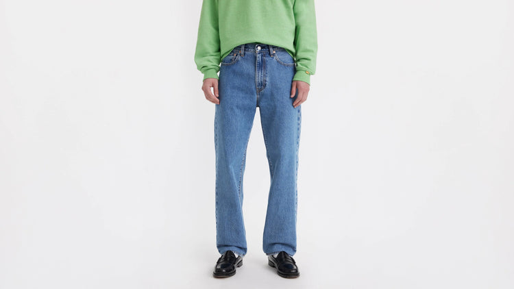 Person wearing a green sweater and blue jeans on a white background