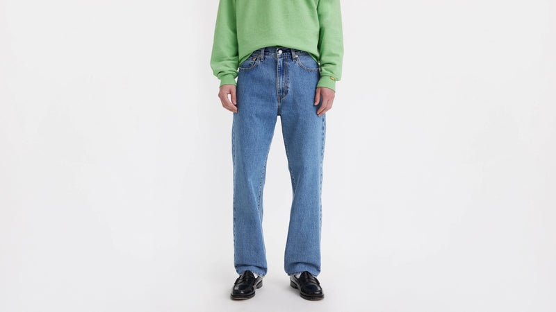 Person wearing a green sweater and blue jeans on a white background