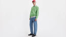 Person wearing a green sweater and blue Levi's jeans on a white background