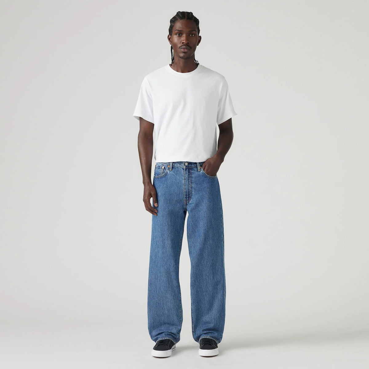 Man wearing a white t-shirt and blue jeans on a plain background