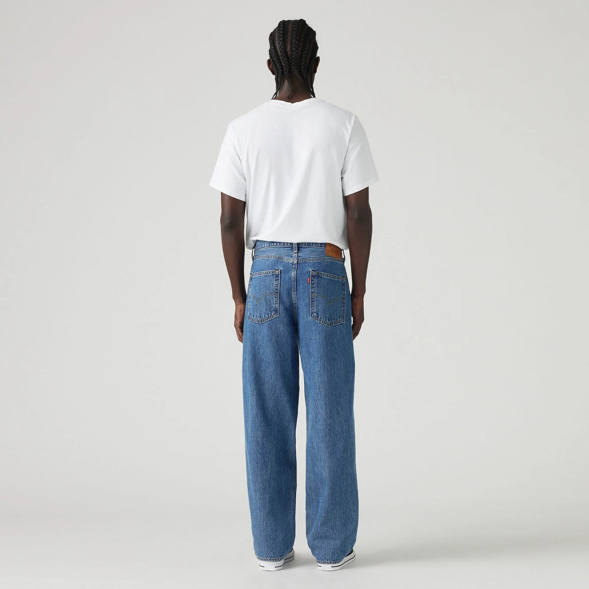 Person wearing blue jeans and a white t-shirt on a plain background
