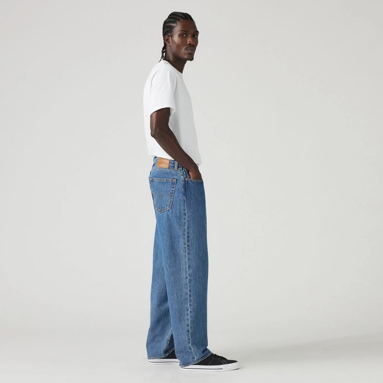 Person wearing a white t-shirt and blue jeans on a plain background