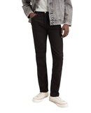 Man wearing a gray denim jacket, white shirt, black pants, and white sneakers on a white background