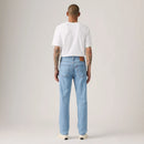 Person wearing light blue jeans and a white t-shirt on a plain background