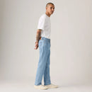 Person wearing light blue jeans and a white t-shirt on a plain background