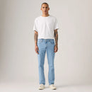 Man wearing a white t-shirt and light blue jeans against a plain background